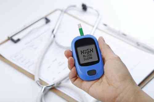 Glucosemeter in een hand die aangeeft dat het bloedsuikergehalte veel te hoog is.